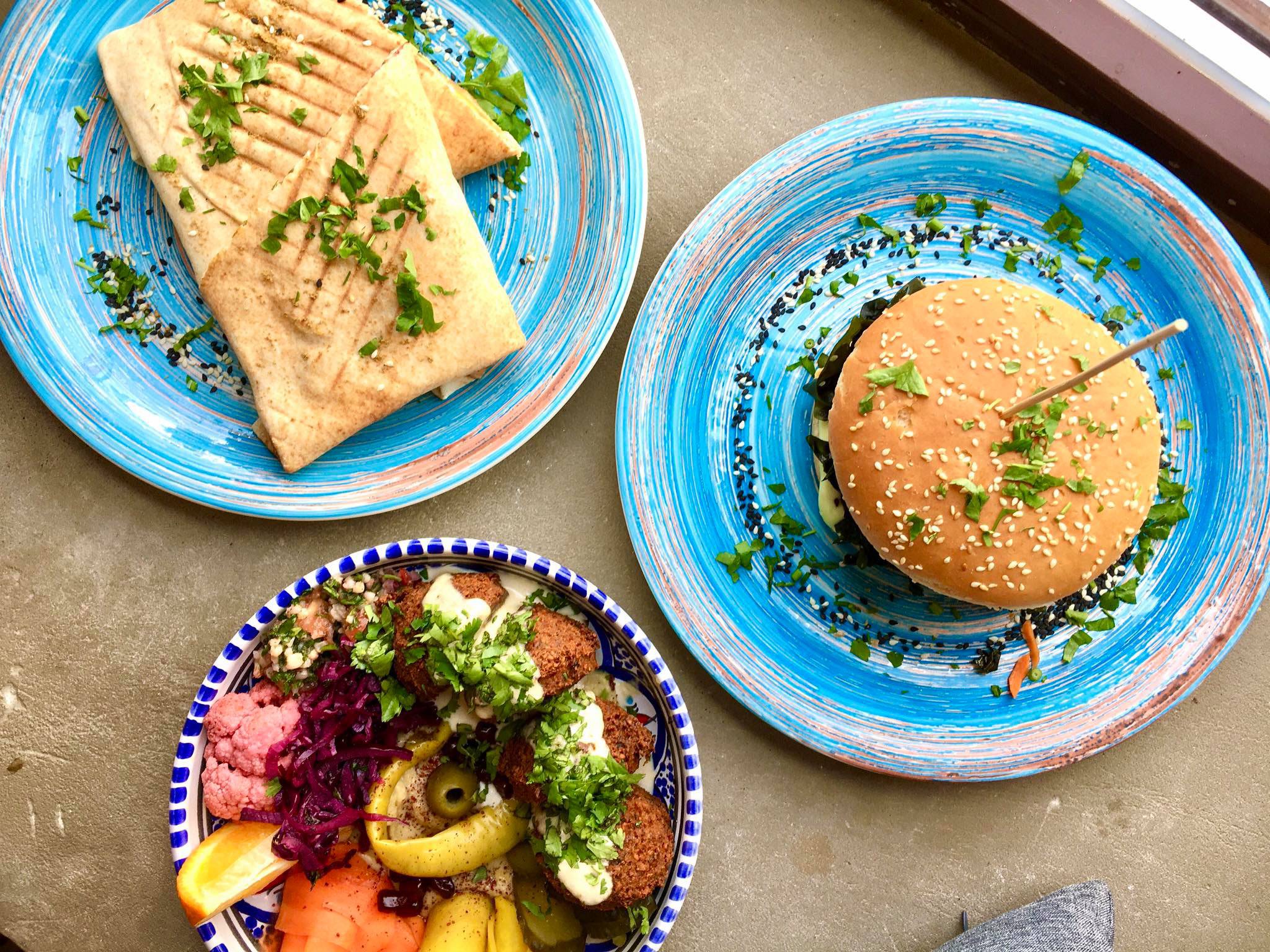 Zdjęcie zrobione z góry - widać na nim trzy talerze z wegańskim jedzeniem w restauracji Falla.