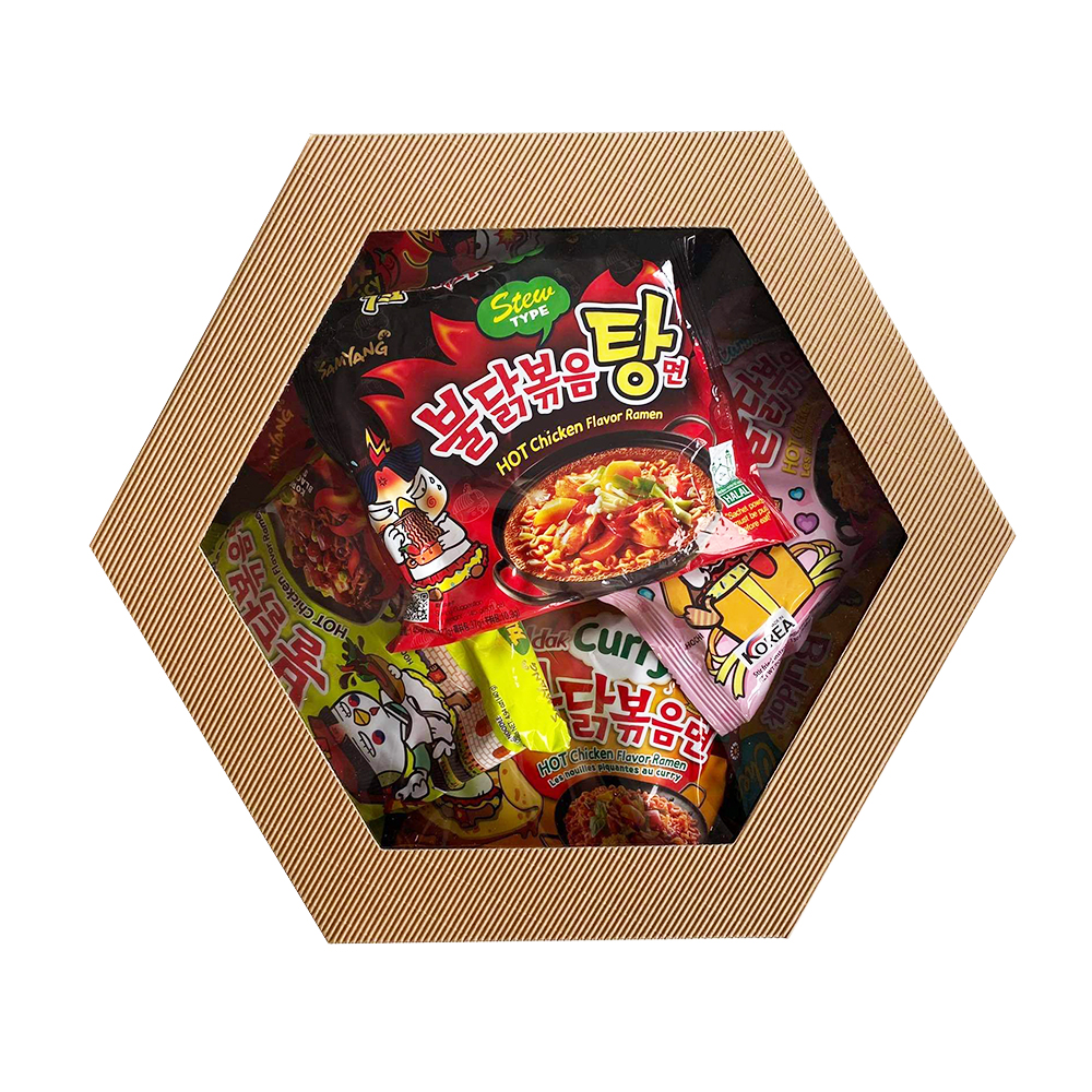 Na zdjęciu widać tekturowe pudełko z przeźroczystym wieczkiem. W pudełku znajdują się koreańskie zupki błyskawiczne w kolorowych opakowaniach.
