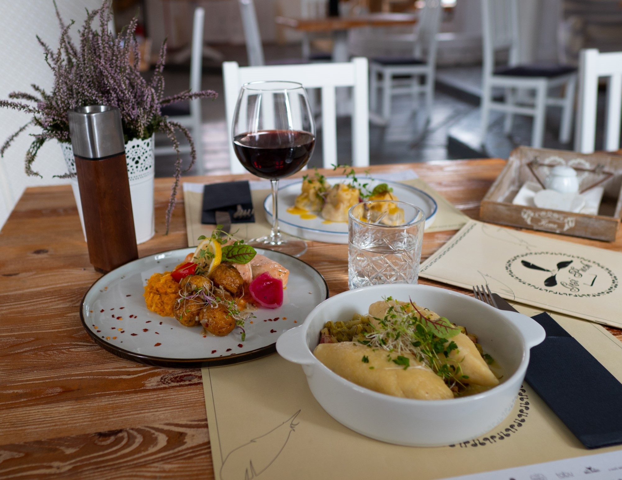 Na zdjęciu widać stół eleganckiej restauracji zastawiony talerzami z daniami i napojami.