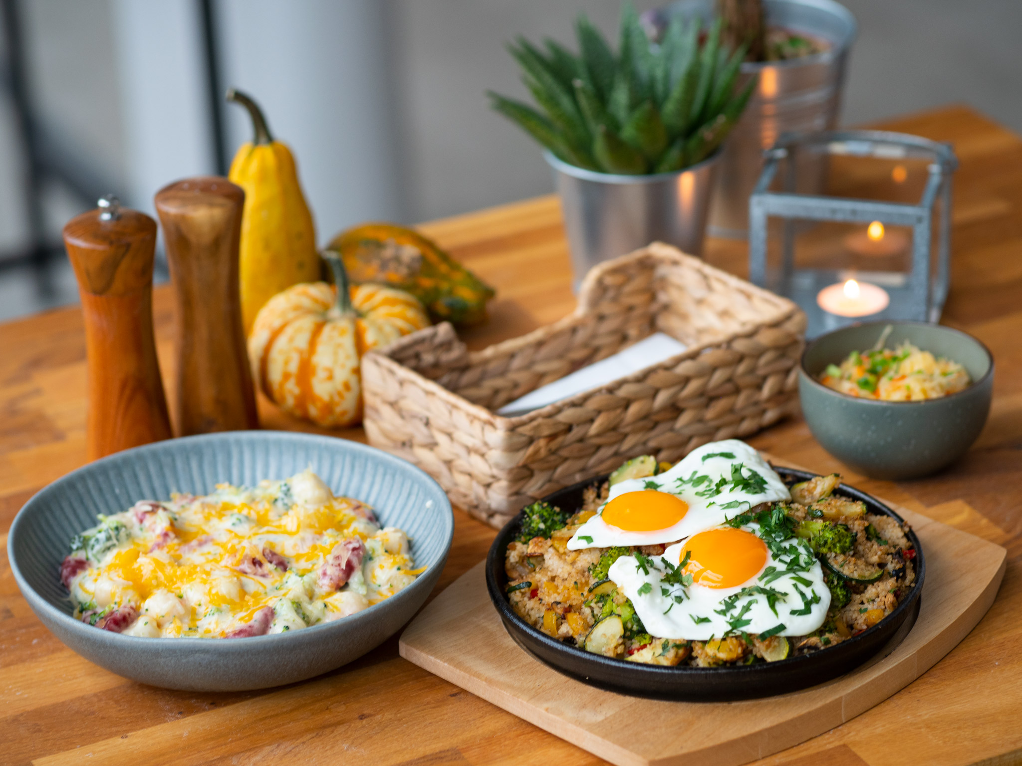 Na zdjęciu widać talerzez jedzeniem ustawione na stole, obok solniczka i pieprzniczka, sztućce i kwiaty